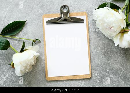 Appunti mockup con peonie su fondo di pietra in cemento. Disposizione piatta, vista dall'alto. Wedding planner, per fare lista, concetto di checklist. Foto Stock