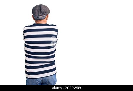 Uomo anziano bello che indossa maschera di scasso e t-shirt in piedi indietro guardando via con le braccia incrociate Foto Stock