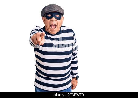 Uomo anziano bello che indossa maschera di scasso e t-shirt puntando dispiaciuto e frustrato alla macchina fotografica, arrabbiato e furioso con voi Foto Stock