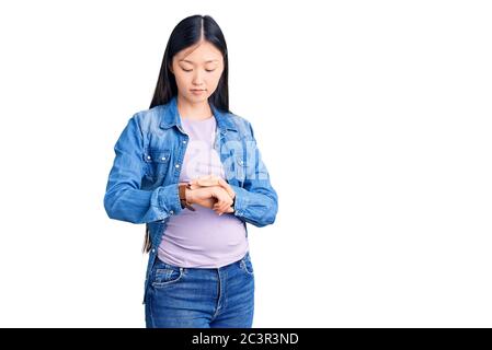 Giovane bella donna cinese incinta attesa bambino che controlla il tempo sul polso orologio, rilassato e sicuro Foto Stock