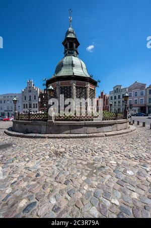 Wismar, Germania, 15 giugno 2020: Mercato con fontana storica, nome tedesco Wasserkunst, nel centro storico di Wismar, contro un cielo blu, l'hanse Foto Stock