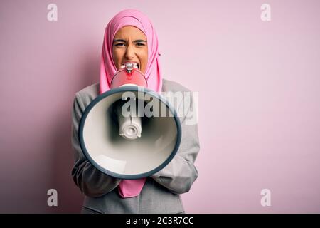 Business arab donna indossare hijab gridando arrabbiato per protesta attraverso il megafono. Urlando eccitato sulla conversazione ludspeaker e urlando le notizie Foto Stock