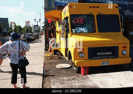 Persone che mantengono una distanza di 2 m COVID sicuro mentre si accodano per il carro chip a Bank e Sunnyside, Ottawa, Ontario, Canada. Foto Stock