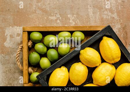 vista dall'alto di limoni e lime in scatole di legno sulla superficie resistente alle intemperie Foto Stock