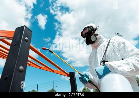 specialista professionale in tuta e respiratore disinfettante per terreni sportivi in parco durante la pandemia di covid-19 Foto Stock