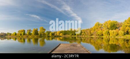 Colori foglie di alberi riflessi in acque tranquille stagno in una bella giornata di autunno. Alberi d'autunno luminosi con cielo tranquillo, foglie d'autunno sul lago Foto Stock