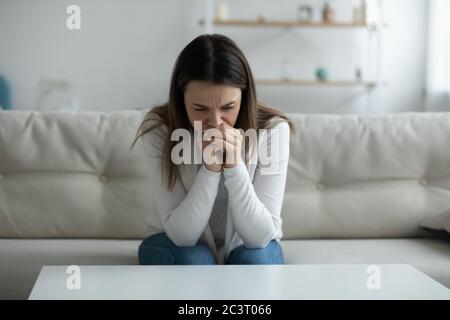 Giovane donna depressa che piange seduta su divano da sola a casa Foto Stock