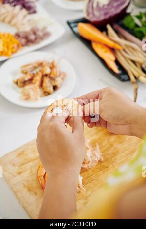 Donna che spellano i gamberi cotti quando si preparano involtini primaverili o sushi a casa Foto Stock