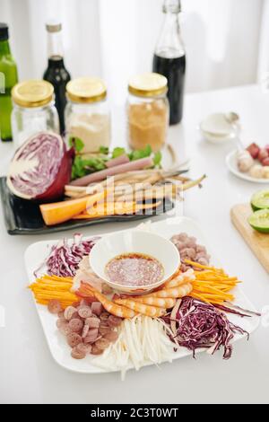 Piatto grande con gamberi bolliti e verdure tagliate intorno alla ciotola con salsa di immersione Foto Stock