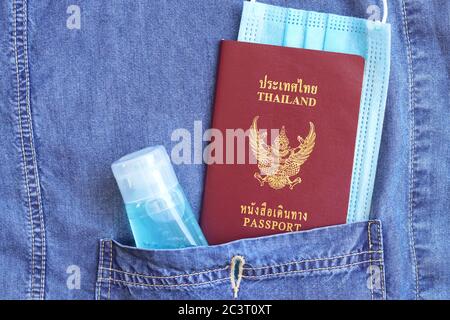 Concetto di turismo in nuovo normale dopo Covid-19 pandemic.Thai Passport viaggio con maschera medica e gel igienizzante per le mani in tasca jean con spazio per la copia. Foto Stock
