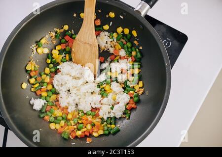 Persona frittura riso in pentola con verdure varie per la cena, vista dall'alto Foto Stock