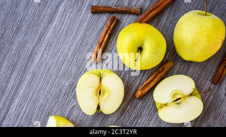 Mele dorate verdi o Granny smith con bastoncini di cannella su sfondo di legno, preparazione di cibo, dessert Foto Stock