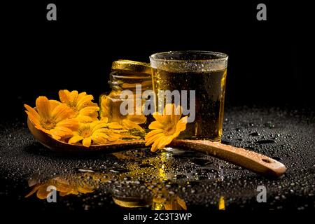 Tè di calendula essiccato in un cucchiaio su sfondo nero Foto Stock