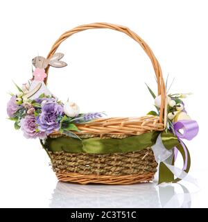 Cestino di Pasqua su sfondo bianco. Decorata con fiori viola e una piccola lepre decorativa in legno. Foto Stock