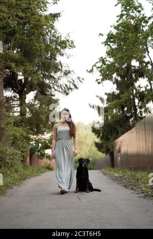 Donna brunette a piedi con cane nero in parco estate Foto Stock