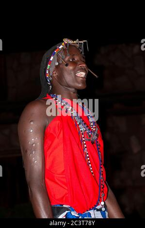 Uomo Maasai sorridente indossando abbigliamento tradizionale, nella Riserva Nazionale di Maasai Mara. Kenya. Africa. Foto Stock