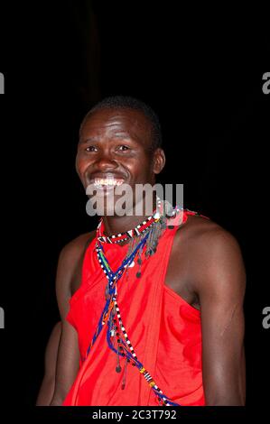 Uomo Maasai sorridente indossando abbigliamento tradizionale, nella Riserva Nazionale di Maasai Mara. Kenya. Africa. Foto Stock