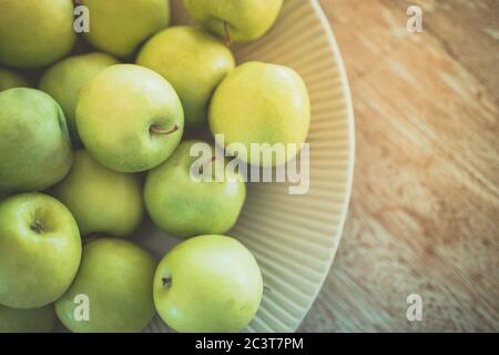 Mele verdi mature in una ciotola di legno su un vecchio tavolo rustico. Frutta utile su sfondo di legno. Vista dall'alto con spazio per la copia Foto Stock