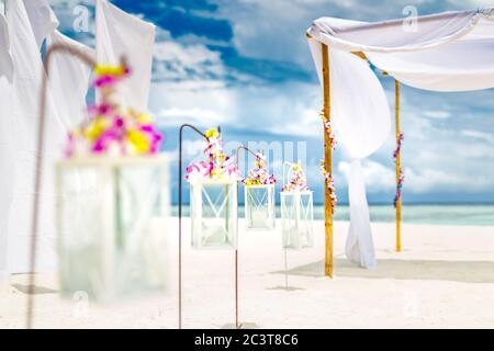 Cerimonia di nozze romantica sulla spiaggia, fiori e candele per elementi di decorazione, sabbia bianca e cielo blu. Amore spiaggia sfondo Foto Stock