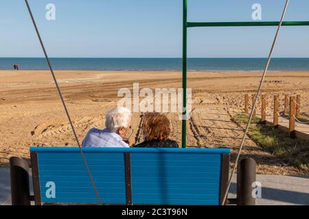 Coppie anziane che si divertono seduti su una panchina che si affaccia sulla spiaggia di Porto Empedocle, Agrigento, Sicilia, Italia Foto Stock