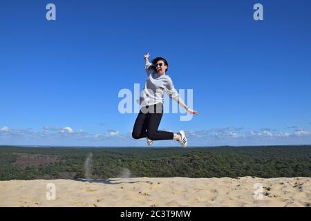 Ragazza allegra che salta con le gambe arricciate Foto Stock