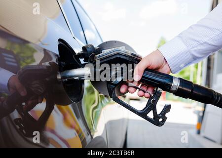 Il trasporto e il concetto di proprietà - uomo di pompaggio del carburante benzina in auto alla stazione di gas Foto Stock