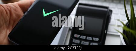 Mani ravvicinate che tengono lo smartphone vicino al terminale Foto Stock