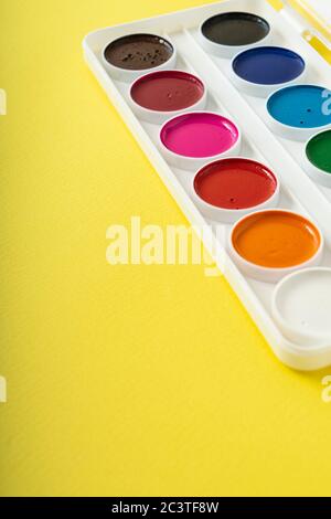 pulire la nuova tavolozza di acquerelli su uno sfondo di carta giallo, copyspace Foto Stock
