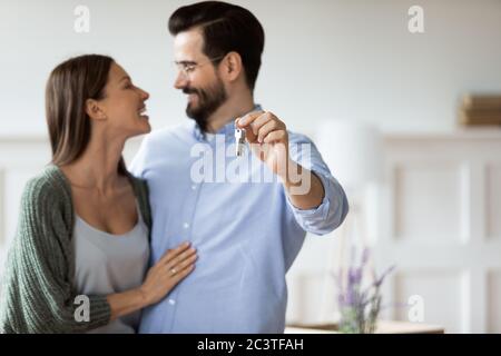 Primo piano felice marito abbracciare moglie e mostrare le chiavi Foto Stock