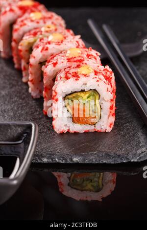 Involtini giapponesi di riso di Uramaki con salmone e cetriolo ricoperti di caviale rosso. Foto Stock