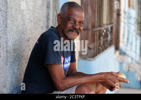 CIENFUEGOS, CUBA - 06 NOVEMBRE: Il povero è seduto con il rotolo in mano sul marciapiede a Cienfuegos, Cuba 06 novembre 2016 Foto Stock