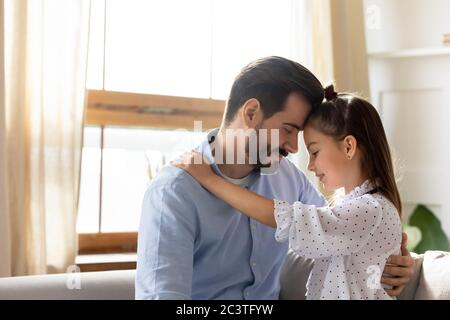 Il padre amorevole e la figlia piccola che toccano le fronte, godendo del momento tenero Foto Stock