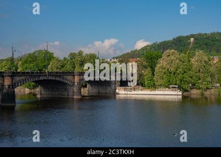 Ponte 'Most Legi' sul fiume Moldava e l'isola 'Strelecky ostrov' a Praga. La collina chiamata Petrin è visibile in lontananza. Foto Stock