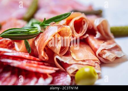 Deliziosi spuntini a base di carne per la cena. Jamon spagnolo a fette, salsicce di pepperoni, prosciutto di manzo servito sul piatto nel ristorante per spuntini Foto Stock