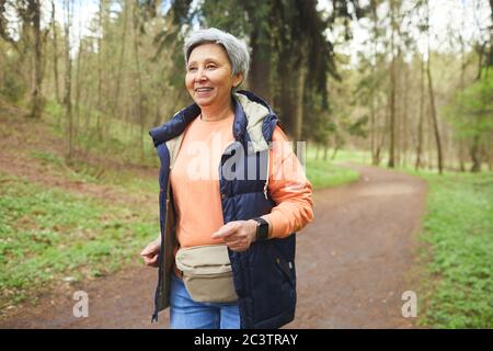 Vita in su ritratto di donna matura attiva che corre in foresta o parco e godendo della natura, copia spazio Foto Stock