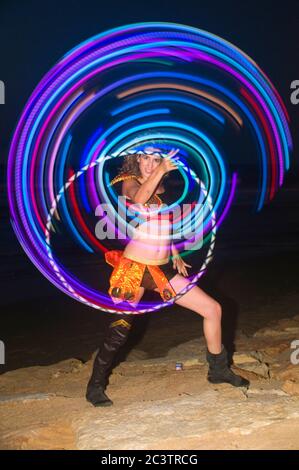Giocoliere psichedelico Hula Hoop sulla spiaggia di notte Foto Stock