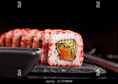 Sushi giapponese con salsa di soia e trissini su sfondo nero. Foto Stock