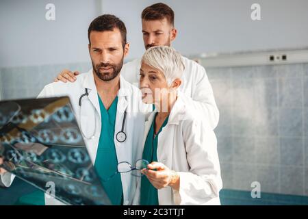 Medici che discutono la diagnosi del paziente guardando i raggi X in un ospedale Foto Stock