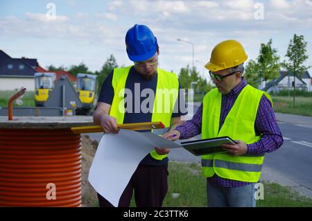 Pianificazione e implementazione del lavoro di squadra. Ingegnere e lavoratore in caschi in un cantiere. Una metafora aziendale per il consenso, il successo e il raggiungimento Foto Stock