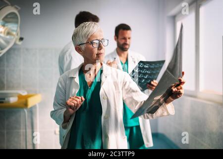 I medici che esaminano un rapporto sui raggi X in ospedale per effettuare la diagnosi Foto Stock