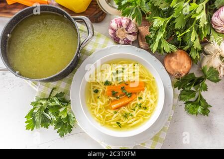 Brodo di zuppa di pollo in un piatto carota cipolla sedano erbe aglio e verdure fresche Foto Stock