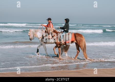 Escursione a cavallo di fronte al mare al tramonto, costa marocchina, Casablanca, Marocco Foto Stock