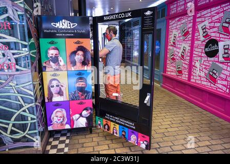 Londra, Regno Unito. 22 giugno 2020. Un membro dello staff carica un distributore automatico in Carnaby Street vendendo al pubblico facemasks dalla società con sede a Londra Maskey. Fondata dall'entreur Adam Freeman per affrontare la domanda di maschere UK-made a prezzi accessibili durante la pandemia di coronavirus in corso, la società di nuova costituzione sta installando i primi distributori automatici di maschere facciali alla moda del Regno Unito in luoghi intorno a Londra, con piani per espandersi ulteriormente. Il 10% del profitto di ogni vendita di facemask viene donato a un ente benefico che sostiene il NHS. Credit: Stephen Chung / Alamy Live News Foto Stock