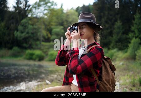 Giovane donna con un cane in una passeggiata all'aperto nella natura estiva, scattando fotografie. Foto Stock