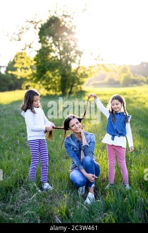 Madre con due piccole figlie che si divertono all'aperto nella natura primaverile. Foto Stock