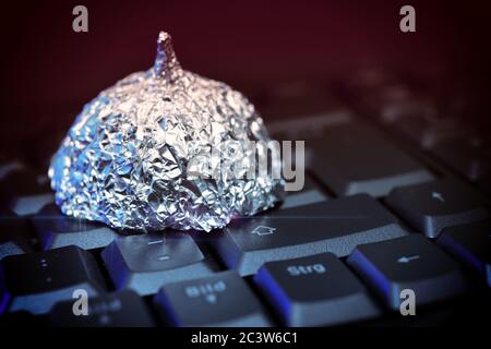 Cappello in lamina di stagno sulla tastiera del computer, foto di simbolo per teorie di cospirazione su Internet, Aluhut auf Computertastatur, Symbolfoto für Verschwörungstheo Foto Stock