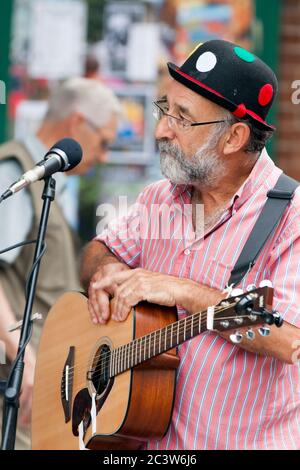 Il chitarrista con la band Accoustic Rooster intrattiene le persone che suonano musica country e canzoni folk durante un weekend mattutino a Bucky Doo Square, Bridport. Foto Stock