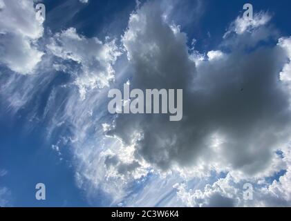 Vista nel cielo blu profondo con stratocumuli e nuvole di cirrus in giornata ventosa annunciando occasionali docce estive pioggia Foto Stock