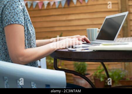 Primo piano di Woman Working from Home su laptop Outdoors in Garden durante il blocco Foto Stock