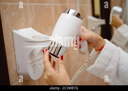 La mano in accappatoio per donna può contenere l'asciugacapelli bianco in hotel Foto Stock